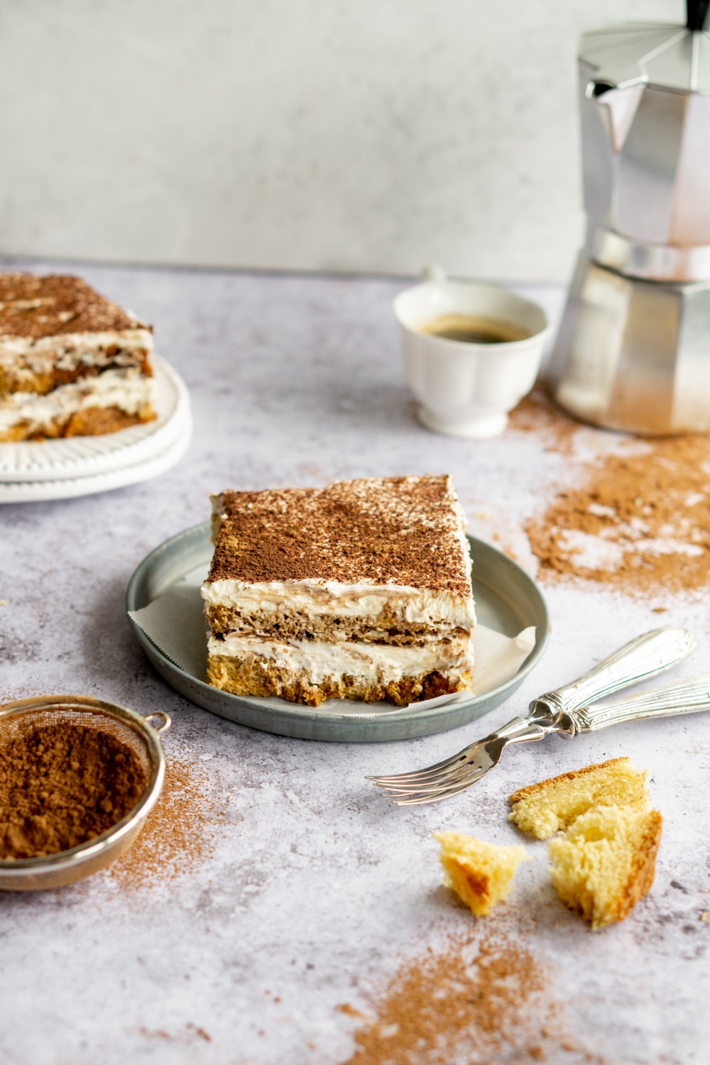 Slice of eggless pandoro tiramisu on a plate with moka pot in the background