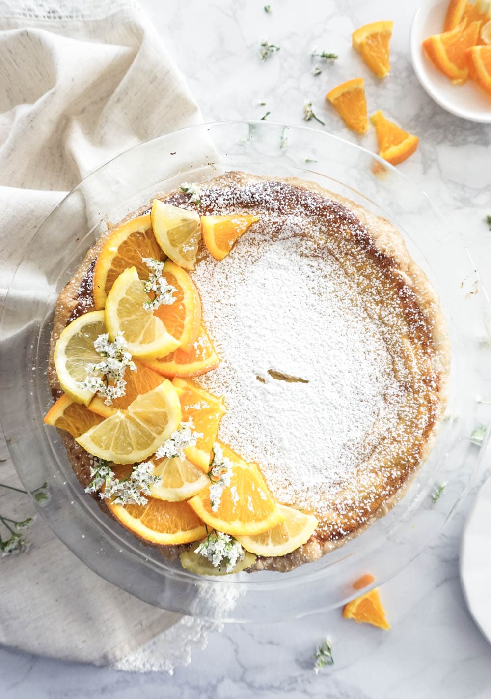 Pastiera napoletana decorated with fresh oranges, lemon and white flowers