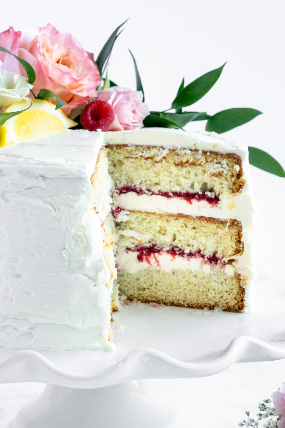 Those layers! Raspberry limoncello cake with limoncello buttercream #pinacooks #limoncellocake #layercake close up shot of limoncello cake with a slice cut out