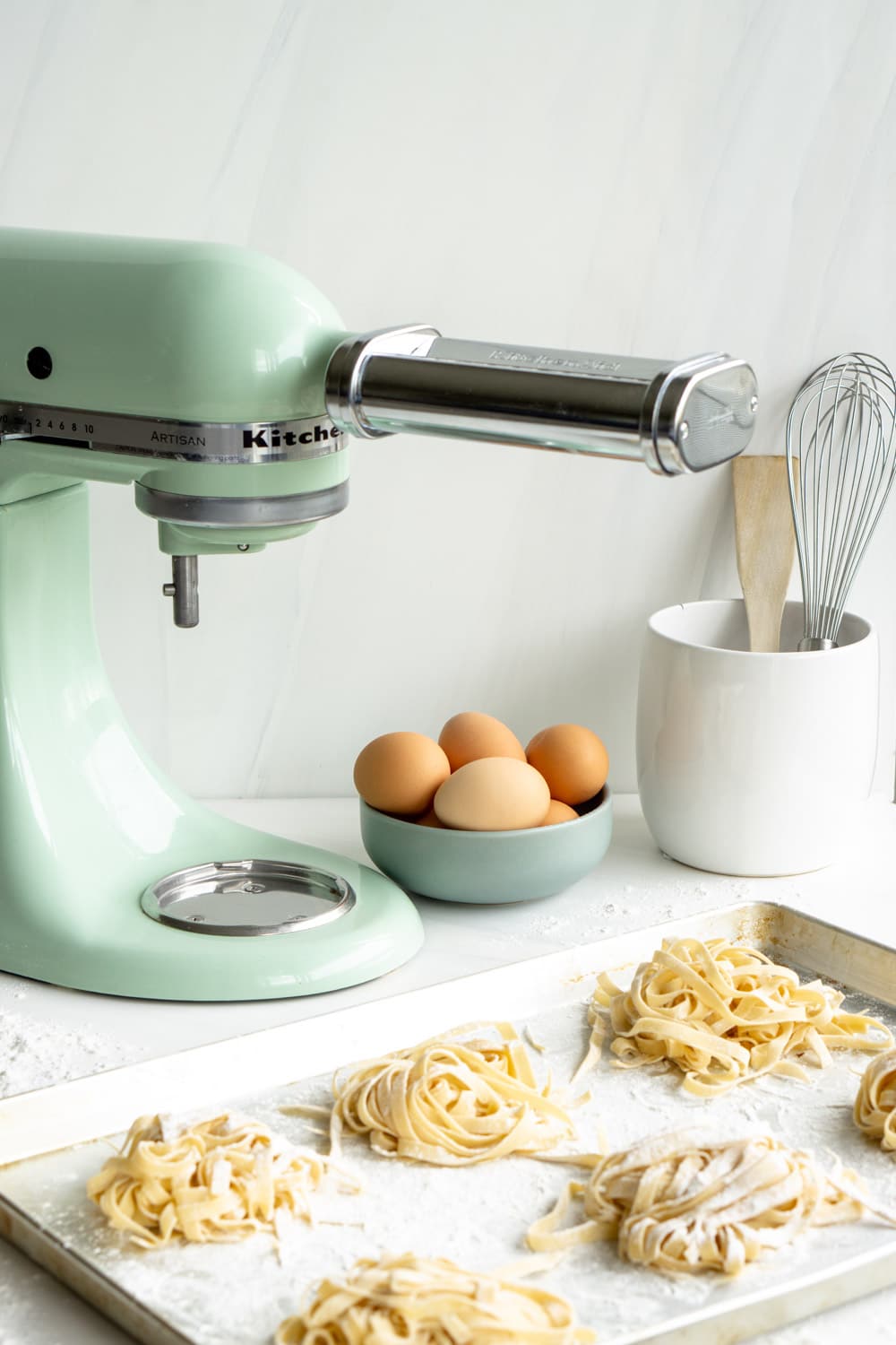 How to make homemade pasta with the KitchenAid pasta attachment. It's easier than you think! #homemadepasta #freshpasta #pinacooks KitchenAid mixer with pasta attachment with homemade pasta in the foreground