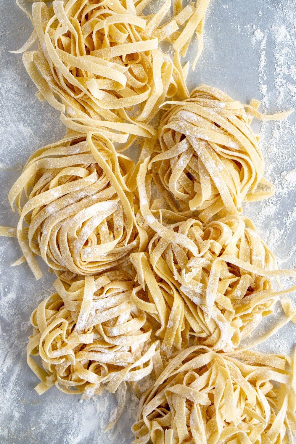 Fresh egg noodle pasta made with the KitchenAid stand mixer. #pinacooks #homemadepasta #freshpasta Homemade pasta on a baking sheet sprinkled with flour