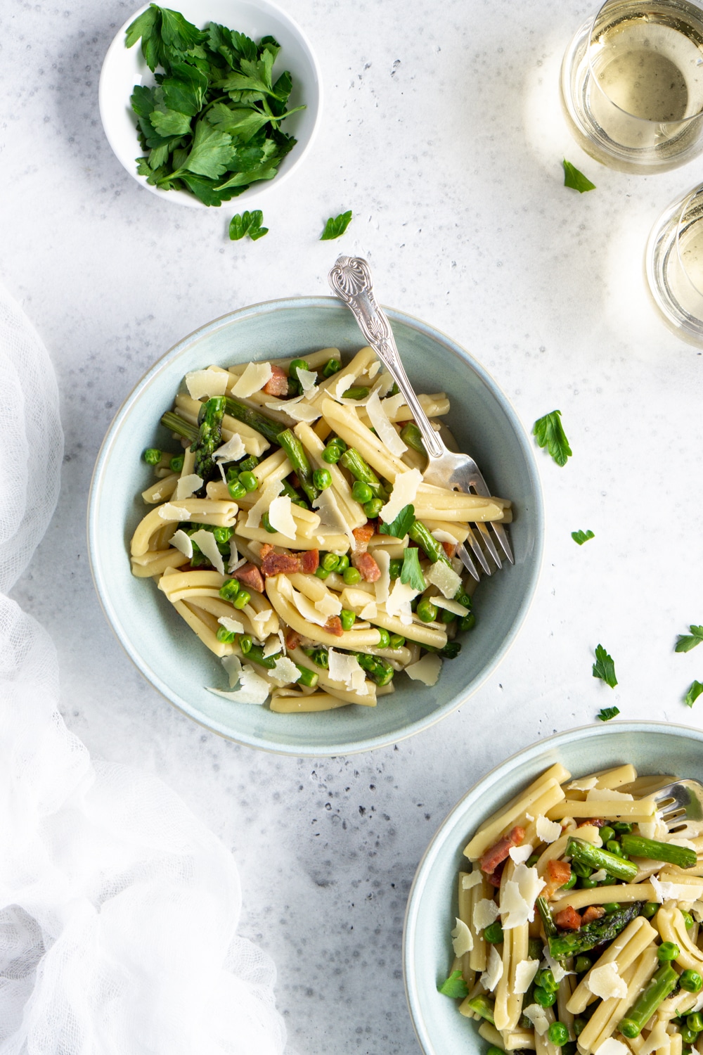 A weeknight meal never looked so good! Asparagus pasta with peas and pancetta that only takes 30 minutes to make! #pinacooks #asparaguspasta #italianrecipes Two bowls of asparagus pasta with pancetta and peas with parsley scattered around