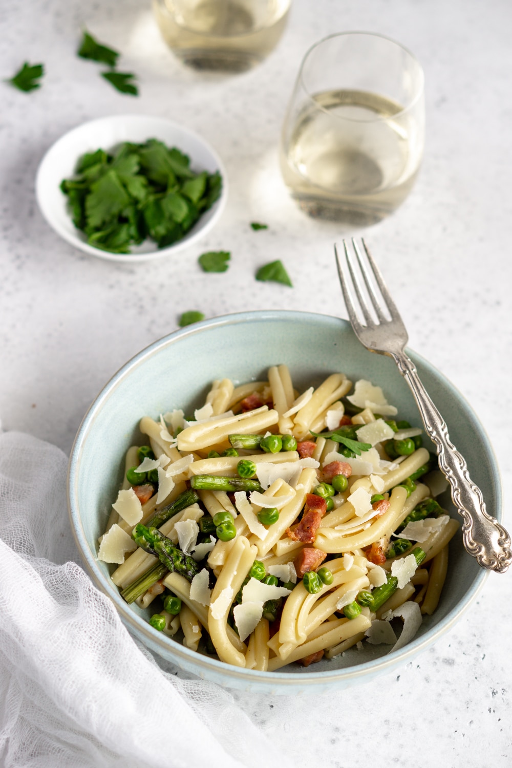 Love this asparagus pasta with peas, pancetta and parmesan! So simple, and only takes 30 minutes to make! asparagus pasta with pancetta and peas with parslry and a glass of wine in the background