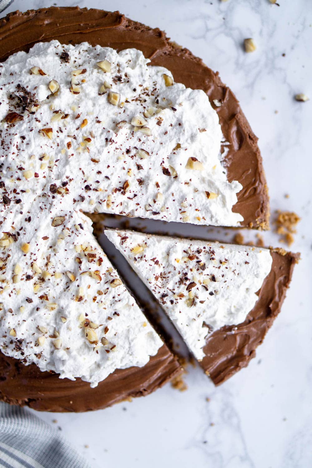 A no-bake nutella tart that will take you 30 minutes to make! The easiest and tastiest dessert when you're in a hurry! #nutella #nutelladessert #nutellatart #pinacooks Overhead shot of nutella tart topped with whipped cream with one slice cut from the tart