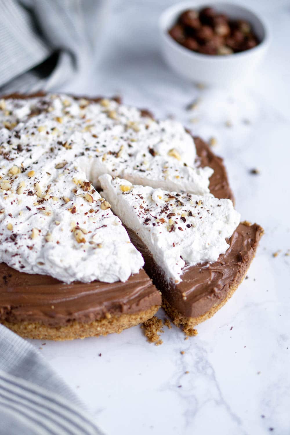 Chocolate Nutella Tart with Whipped Cream and a Bowl of Hazelnuts in Background