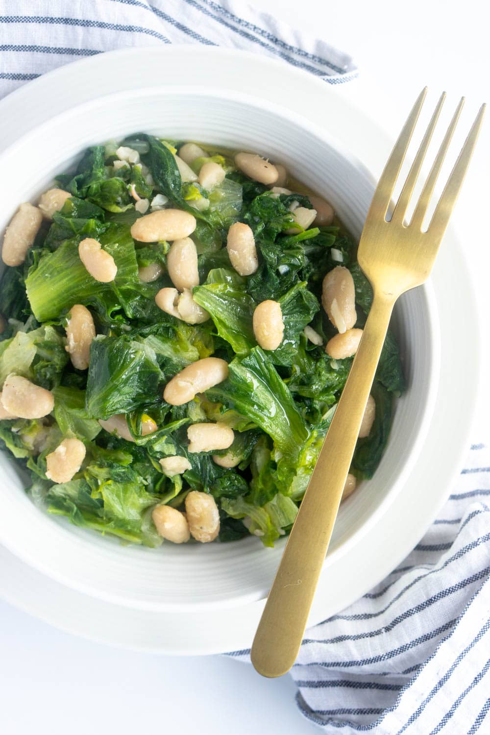 Escarole and beans. A comforting Italian side dish! #pinacooks #italianfood #escarole #sidedish Plate of escarole and beans with a gold fork