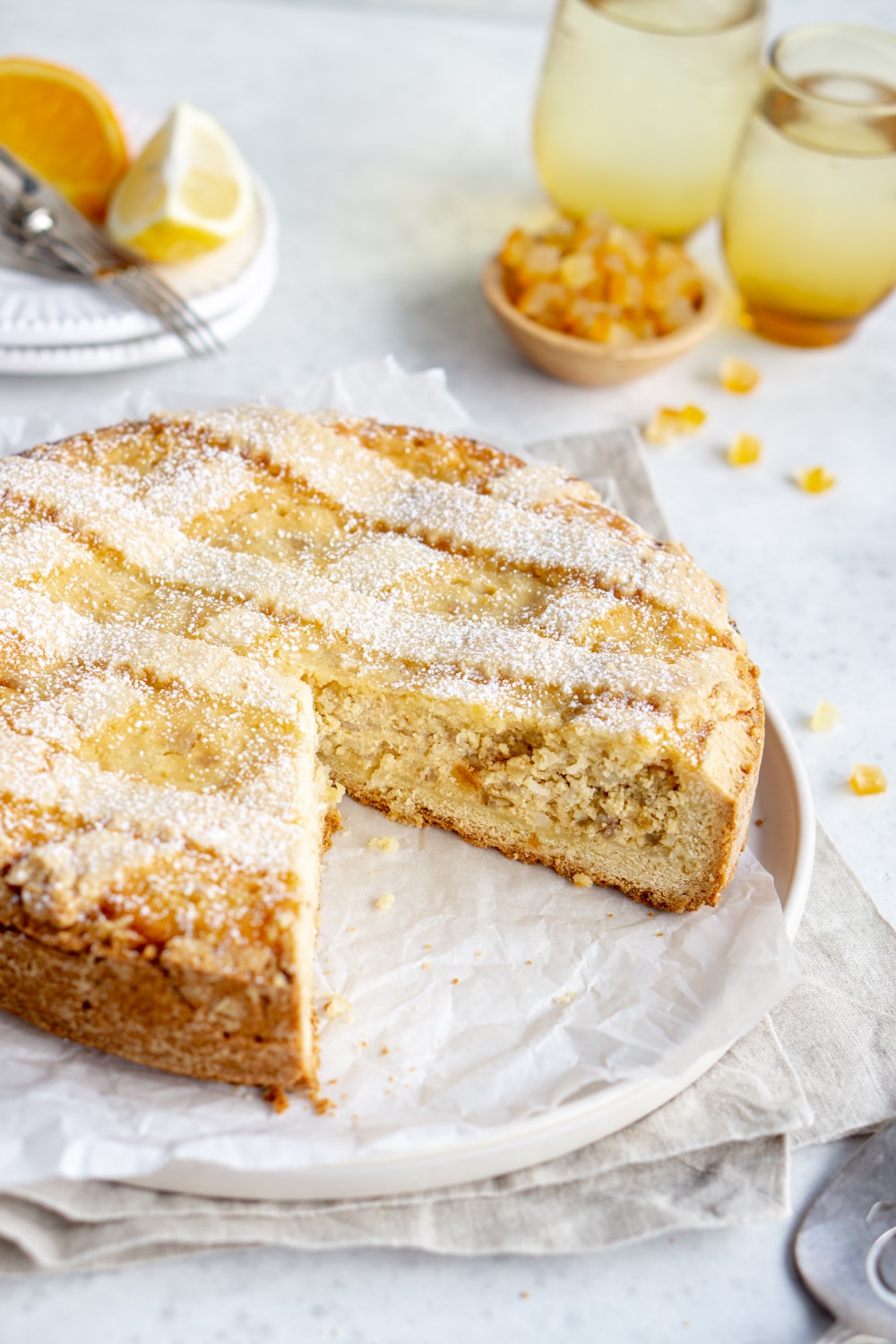 Pastiera Napoletana, an Italian Easter pie on a plate with candied oranges in the background