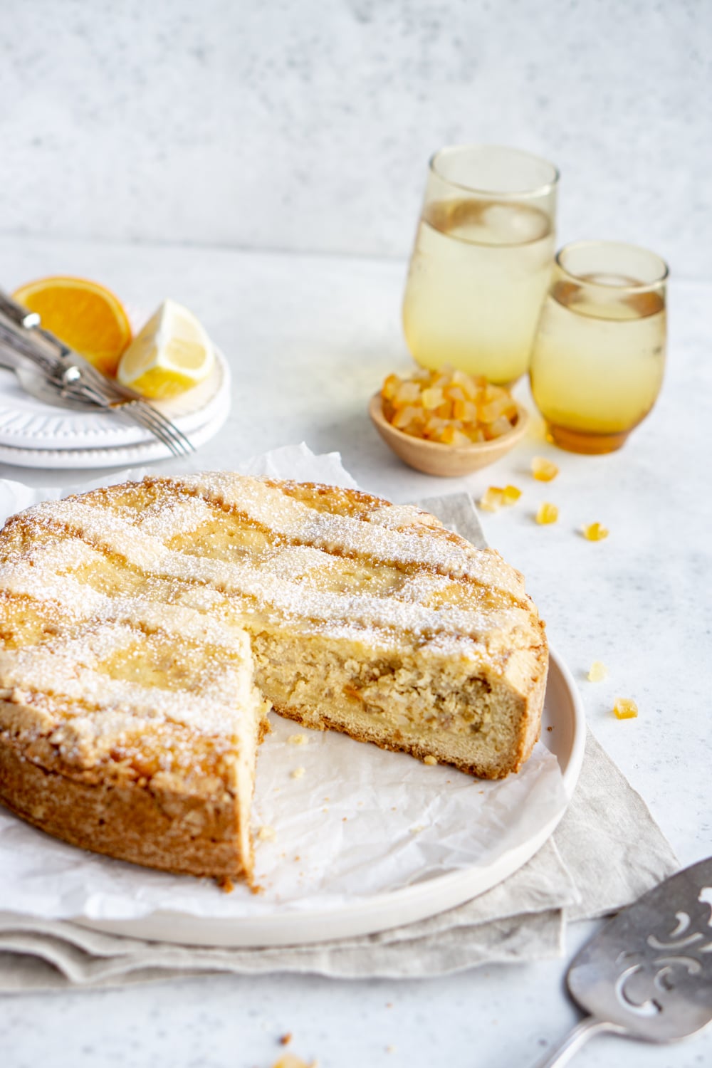 Side angle shot of a pastiera napoletana Italian Easter pie with dessert plates in the background