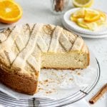A sweet Easter rice pie sitting on a cooling rack with oranges and cinnamon sticks in the background