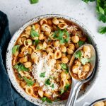 Overhead shot of a bowl of pasta e ceci with two spoons in it