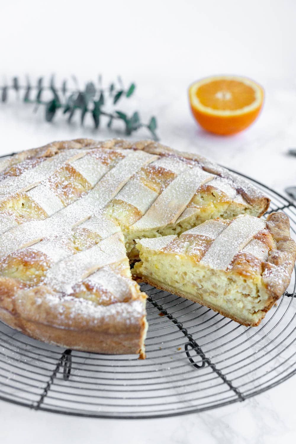 side photo of pastiera napoletana with orange in the background