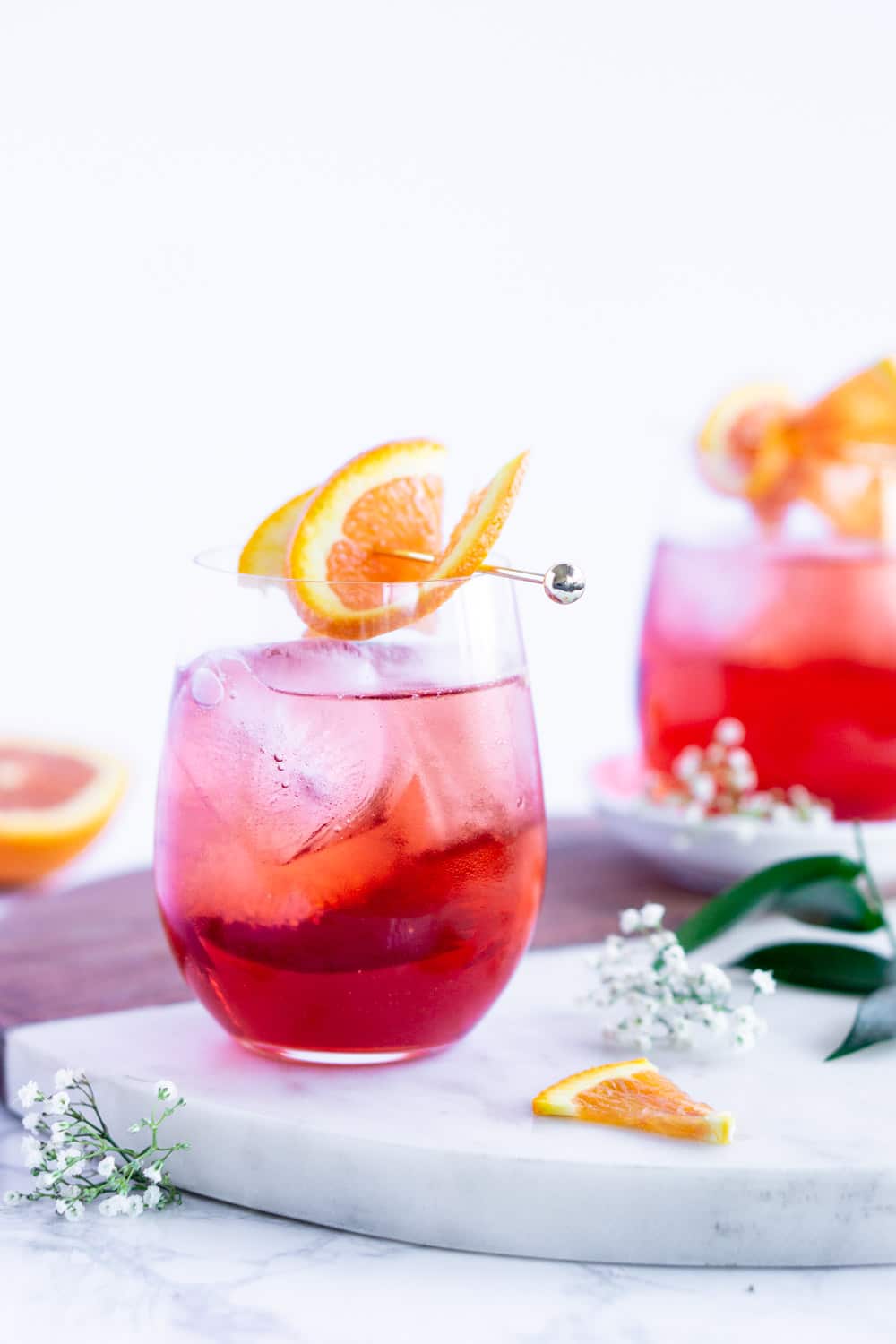 Aperol spritz's cousin - the campari spritz! Such a refreshing cocktail #camparispritz #camparicocktail #pinacooks campari spriz in a stemlass wine glass with another campari spritz in the background