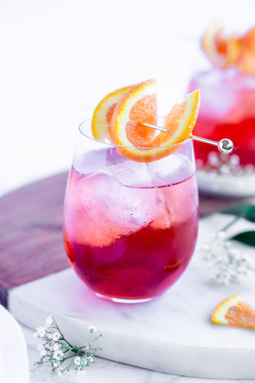 Love a good campari spritz- so quick and easy to put together! #camparicocktail #camparispritz #pinacooks campari spritz cocktail with ice in a stemless wine glass garnished with an orange