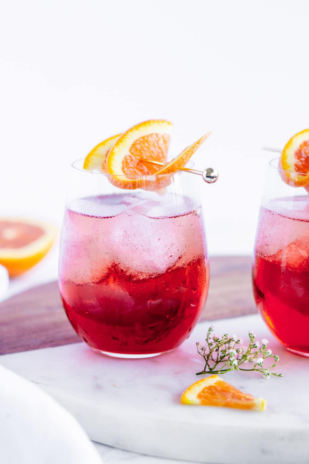 Move over aperol spritz, because the campari spritz is here! Made with campari, prosecco and club soda, it's the perfect appetite-stimulating cocktail #camparispritz #camparicocktail #pinacooks 2 campari spritz cocktails on a marble serving board