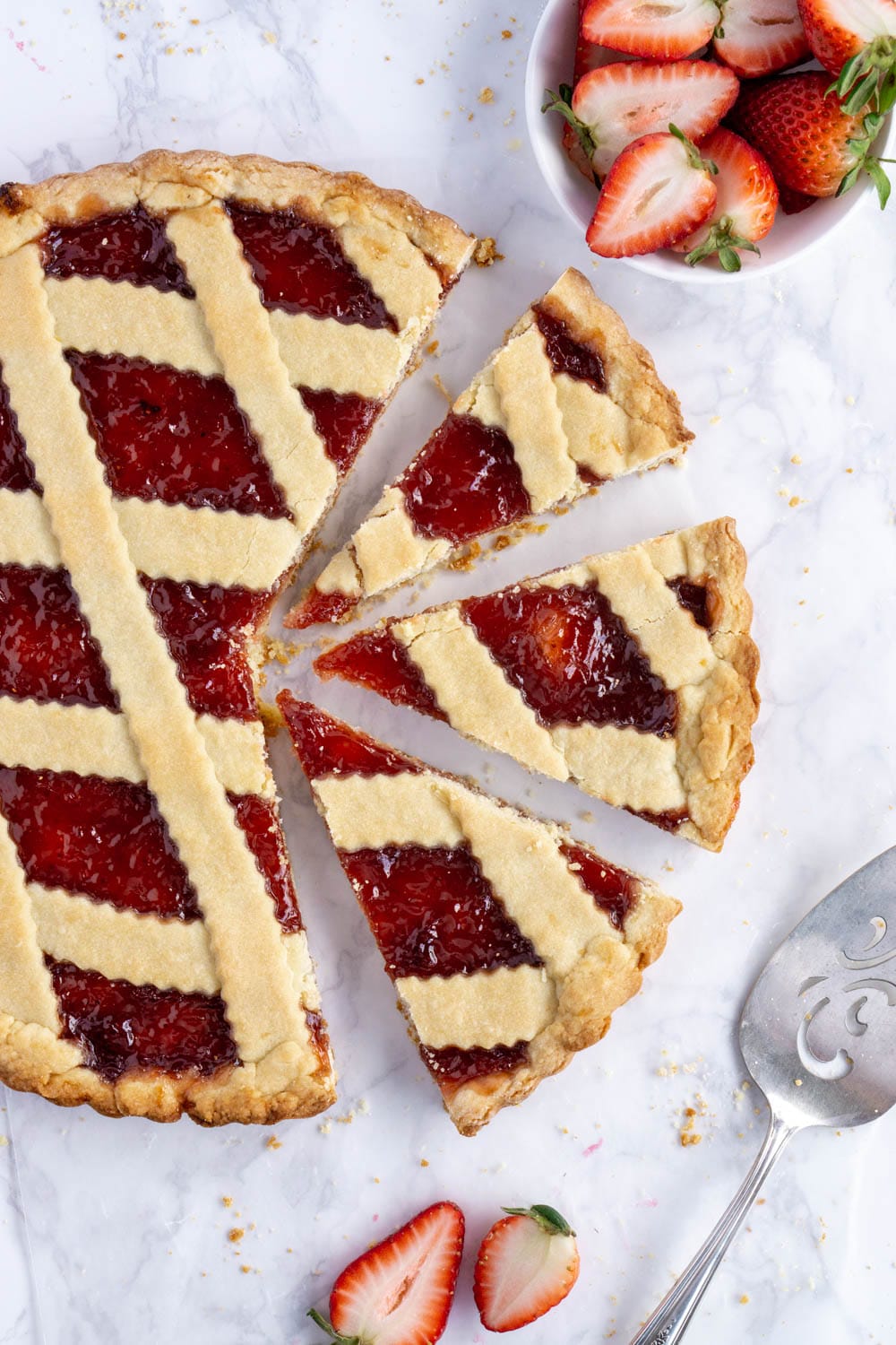 overhead photo of a jam crostata with 3 slices cut out of it
