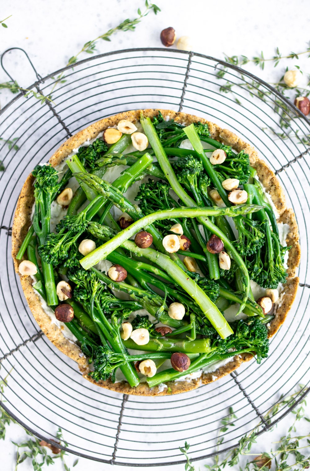 Such an easy appetizer - this asparagus tart with goat cheese and hazelnuts #pinacooks #asparagustart Asparagus tart on a cooling rack surrounded by thyme