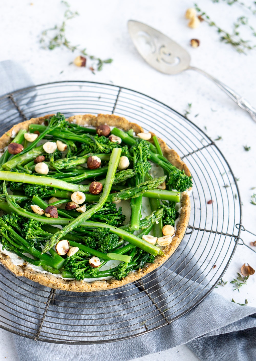 Asparagus and goat cheese tart with toasted hazelnut crust #pinacooks #asparagustart Side view of asparagus tart with a serving spoon in the background