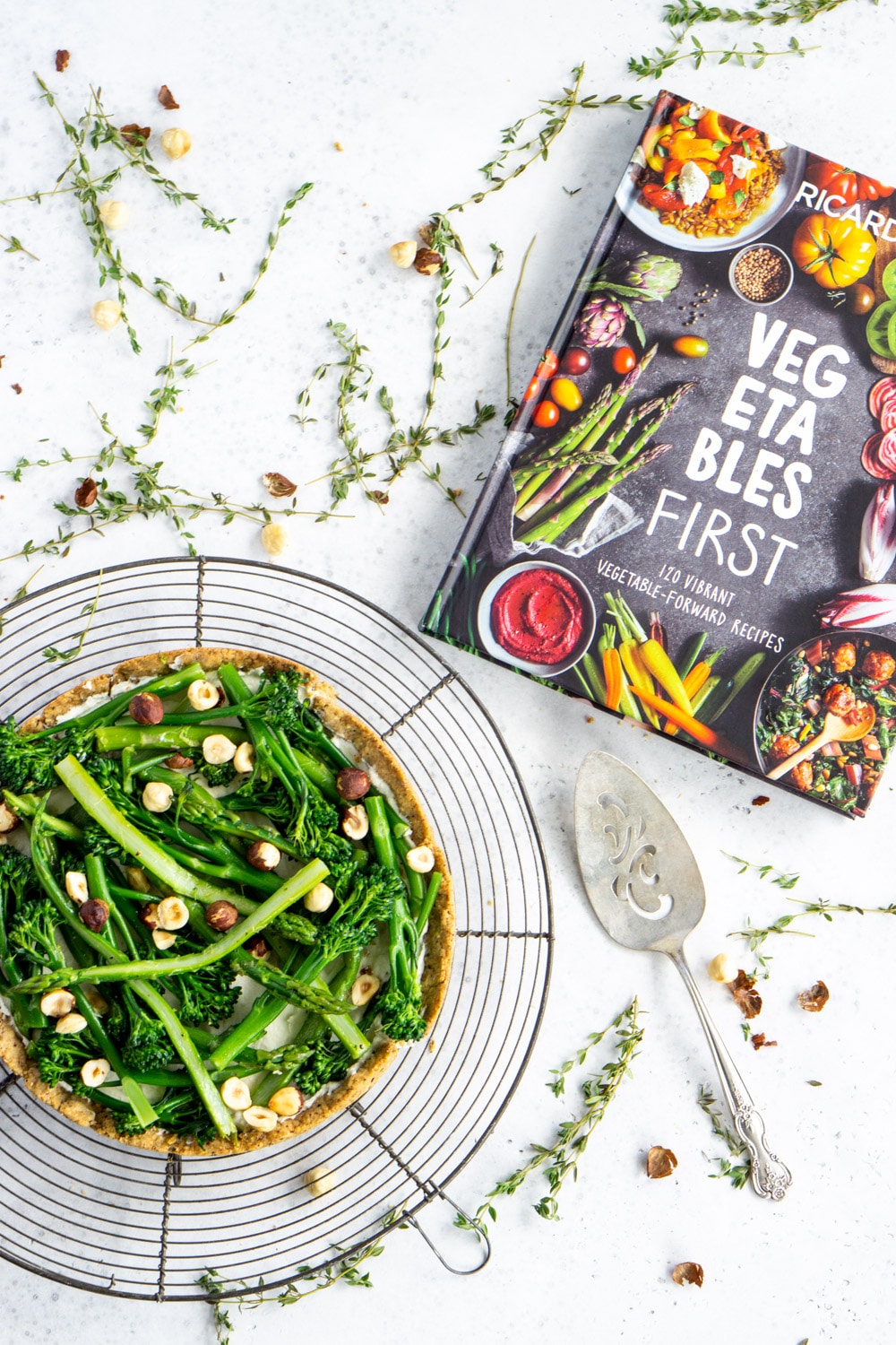 Asparagus tart with toasted hazelnut crust from Ricardo's cookbook, Vegetables First #asparagustart #pinacooks Asparagus tart on a cooling rack and ricardo book to the side