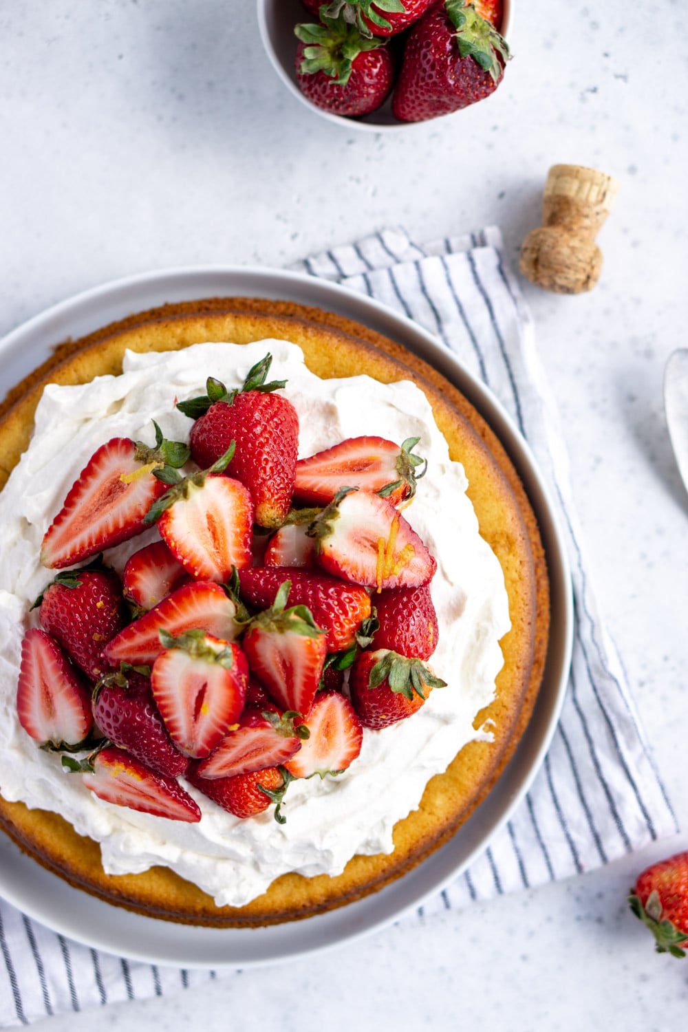 Italian lemon olive oil cake with mascarpone cream and prosecco-soaked strawberries #italiandesserts #oliveoilcake #pinacooks overhead photo of olive oil cake in a dish with a napkin under it