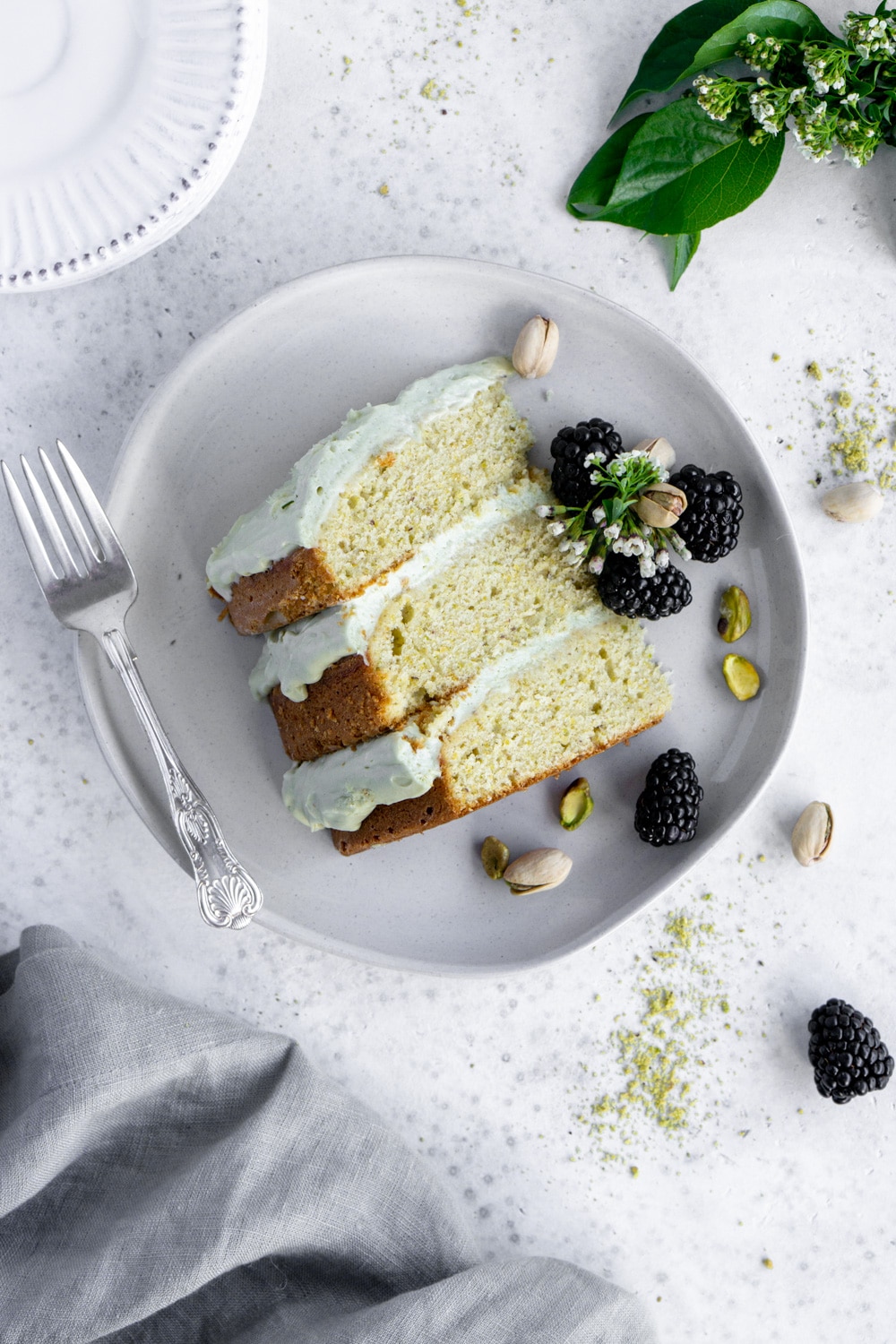Pistachio cake with amazing pistachio whipped cream. Yum! #pinacooks #pistachiocake #italiancake slice of pistachio cake on a plate with blackberries around it