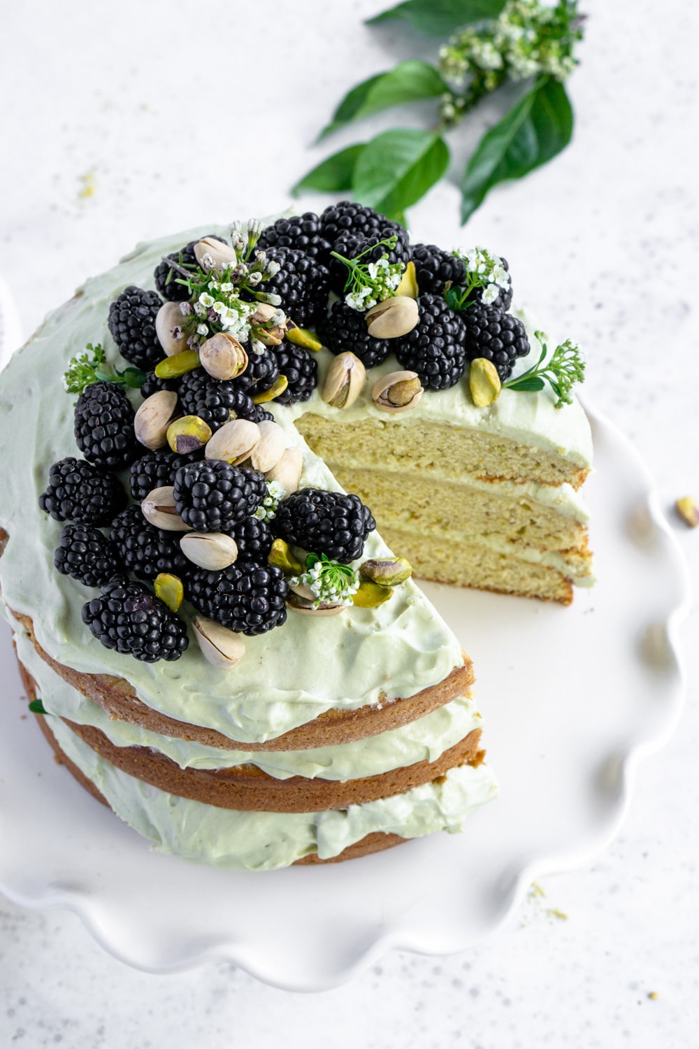 Homemade pistachio cake with delicious pistachio whipped cream #pinacooks #pistachiocake #italiancakes pistachio cake on a plate topped with blackberries and pistachios