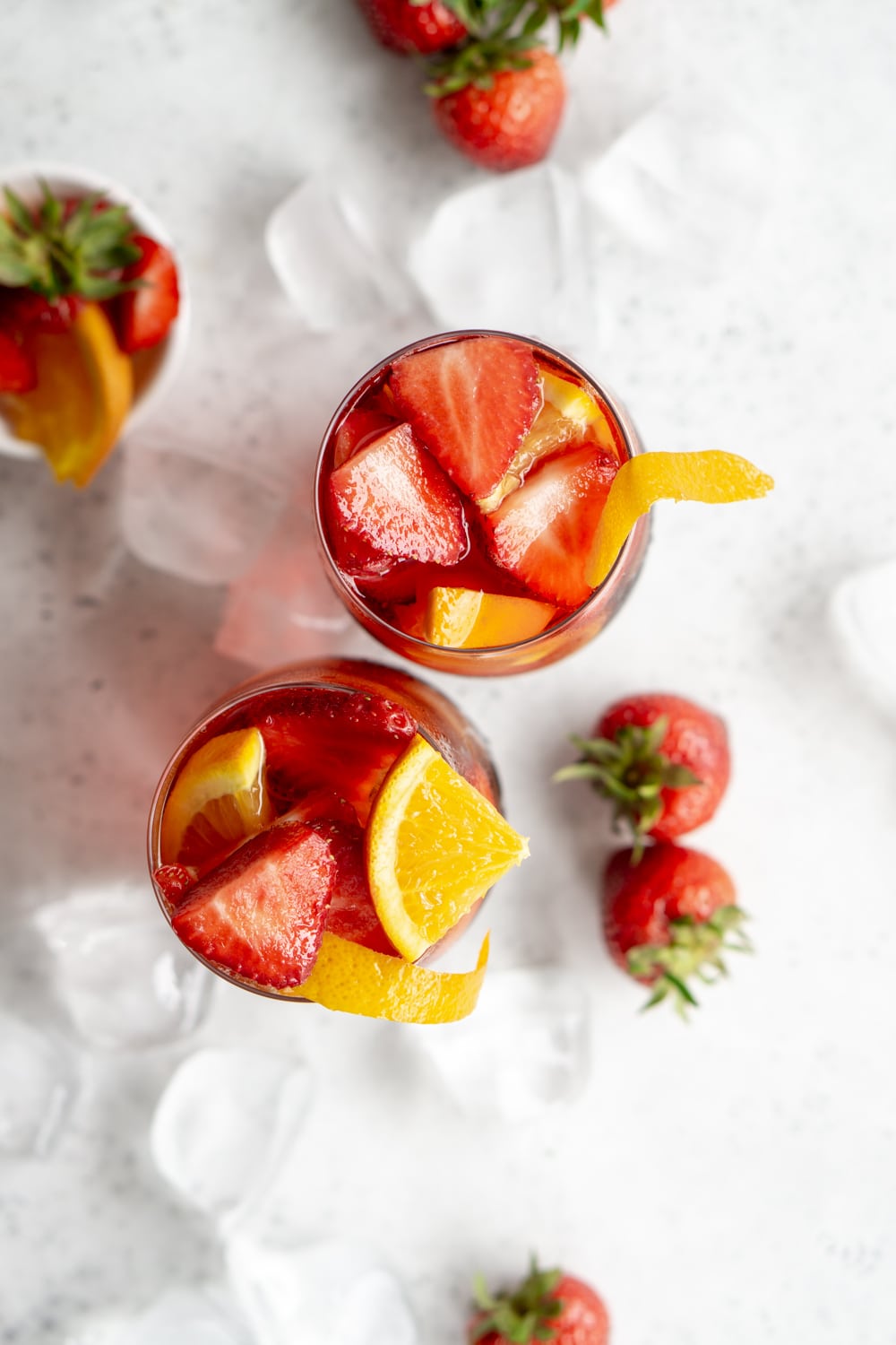 The perfect americano cocktail recipe! It's all about getting the proportions of campari, sweet vermouth and club soda right #italiancocktails #italiandrinks #americanococktail #pinacooks Overhead shot of 2 glasses with americano cocktails in them garnished with oranges and strawberries