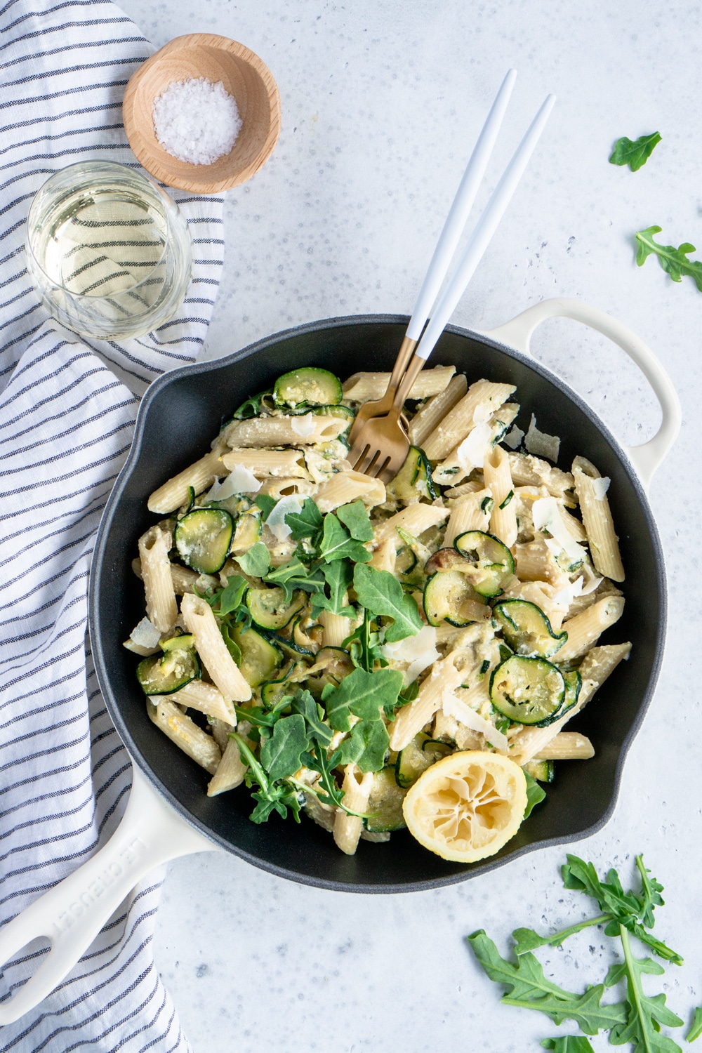 Italian ricotta pasta with zucchini, arugula and parmesan cheese. So many delicious flavors in one dish! #pinacooks #italianfood #ricottapasta Ricotta pasta in a skillet with a glass of wine and a napkin to the side