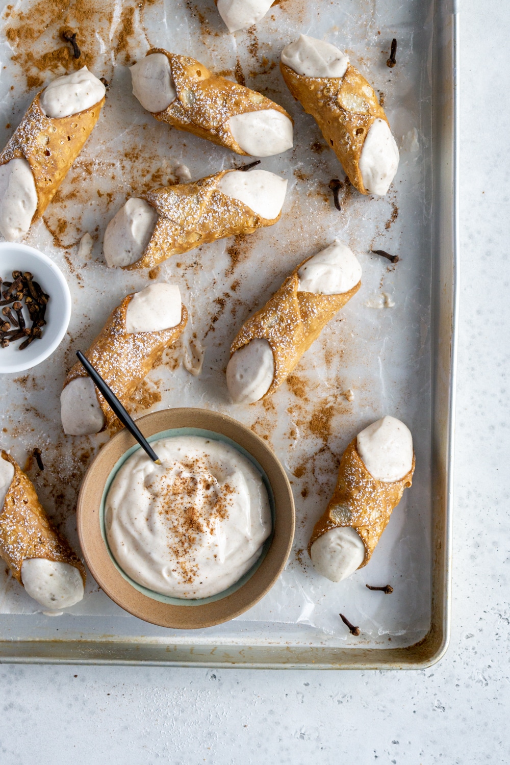 Authentic Italian cannoli cream filling! One of the easiest things to make, ever! #cannolicream #italianfood #pinacooks Cannoli on a baking sheet with a bowl of cannoli cream