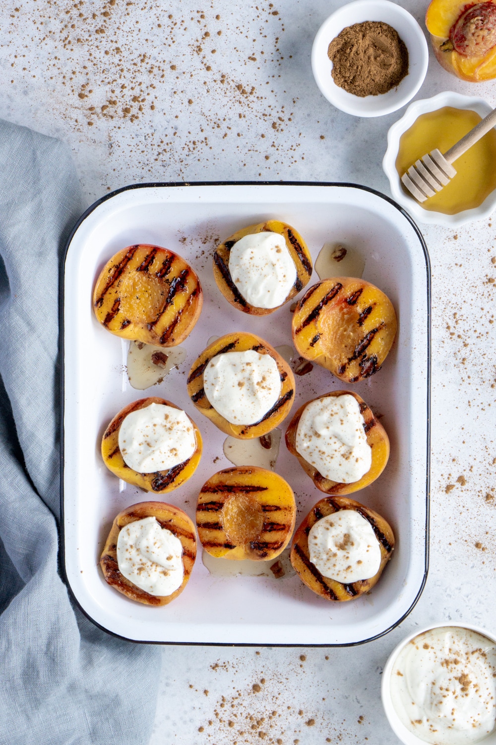 Easy grilled peaches with whipped ricotta, honey, vanilla and cinnamon. A perfect flavor combination! #pinacooks #grilledpeaches #summerdesserts Bunch of grilled peaches in a white pan with a napkin on the side