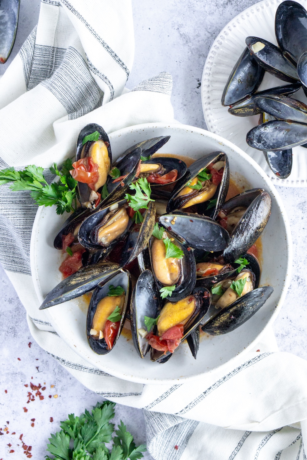 Mussels Italian style: in a garlic, tomato and white wine broth. Totally delicious for dinner! #mussels #steamedmussels #italianfood #pinacooks Plate of mussels sitting on a white napkin