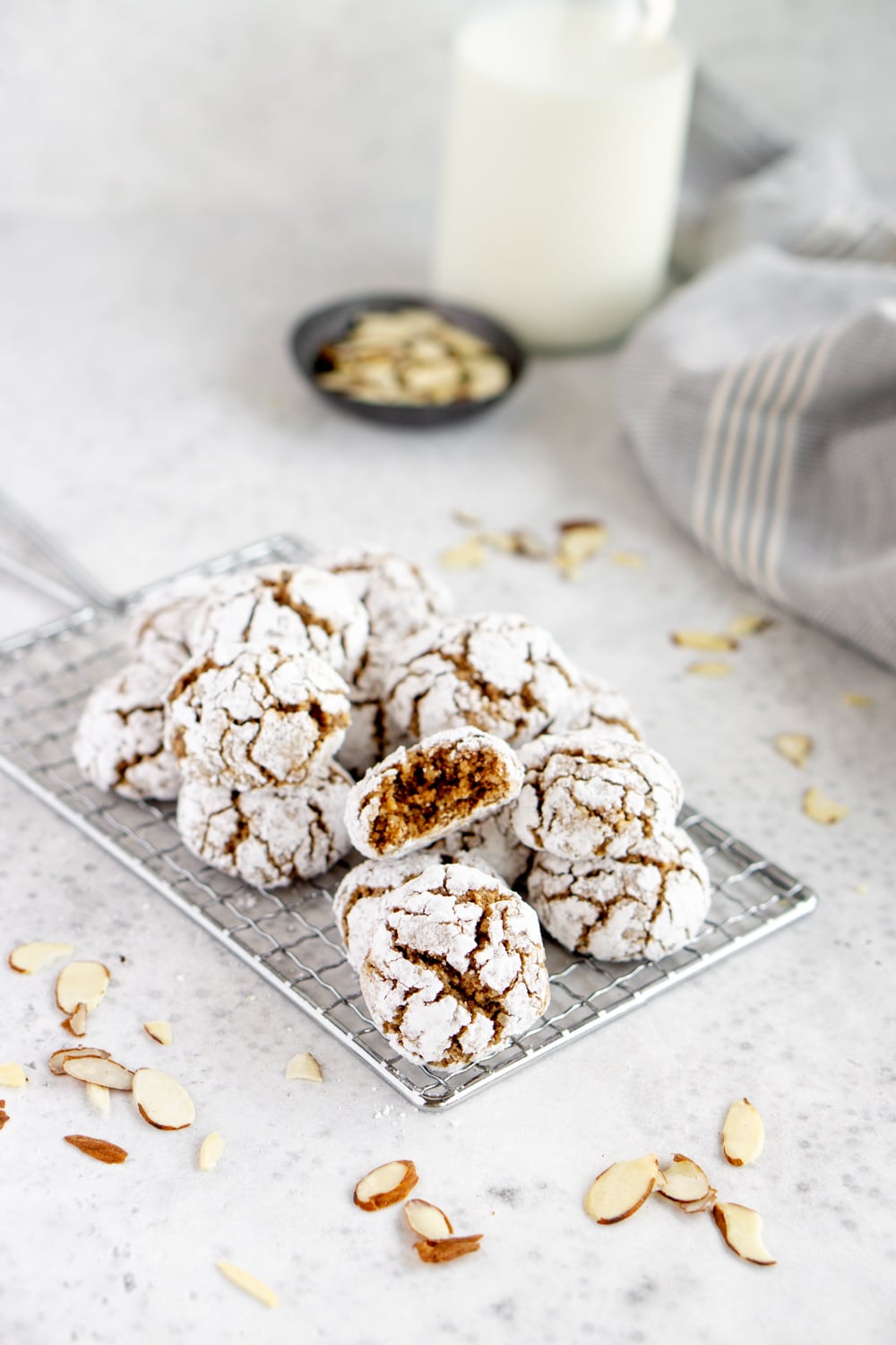 Amaretti cookies on a cookie sheet with milk and almonds in the background