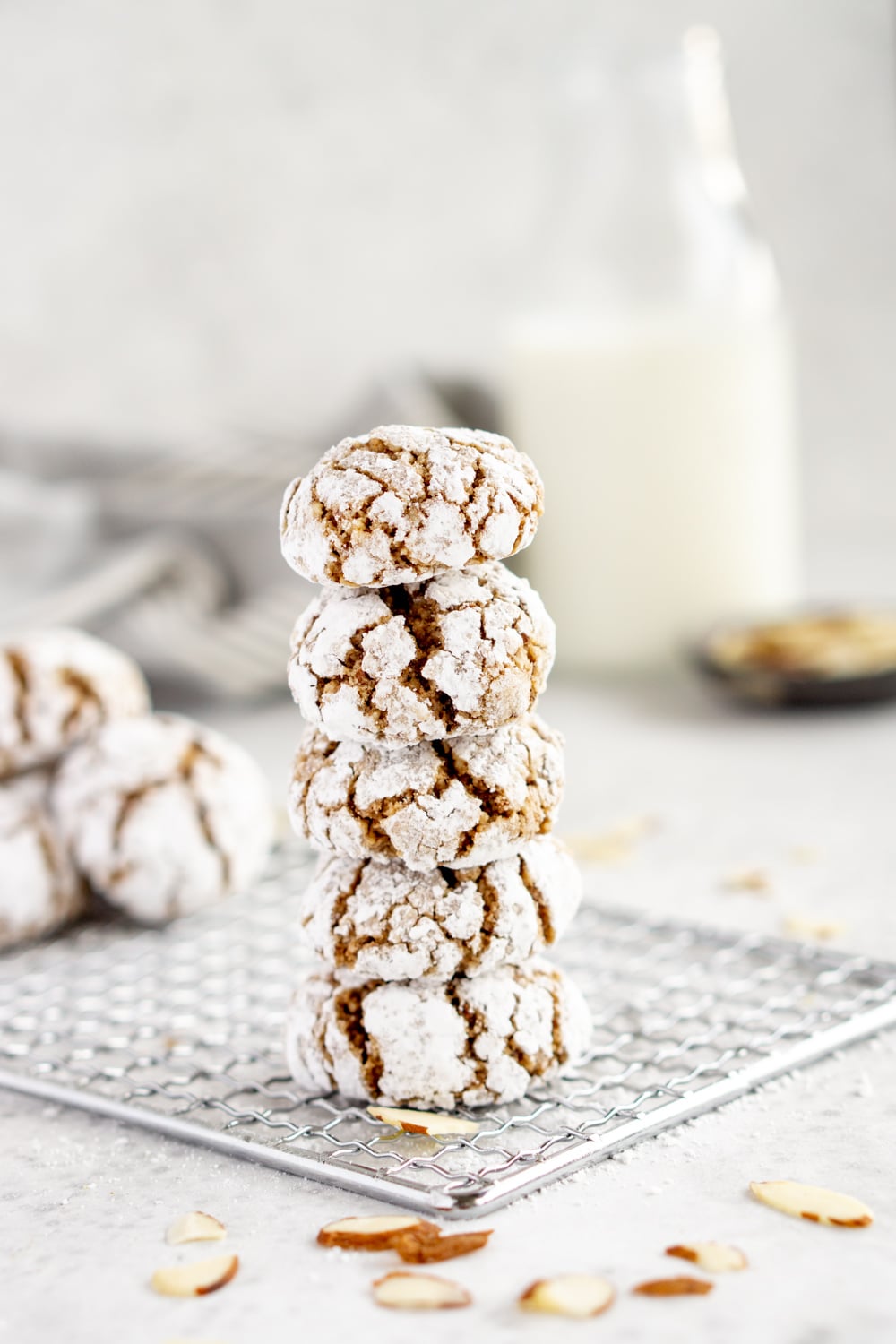 Stacked amaretti cookies on a baking sheet with milk in the background