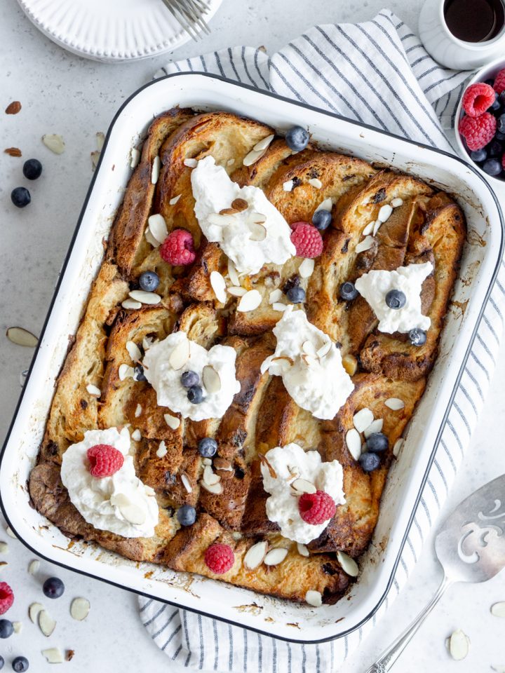 Panettone bread pudding in a baking dish topped with whipped cream and berries