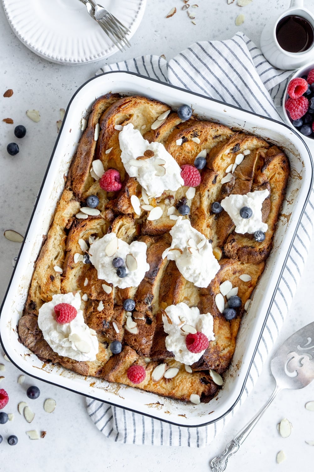 Panettone bread pudding in a baking dish topped with whipped cream and berries