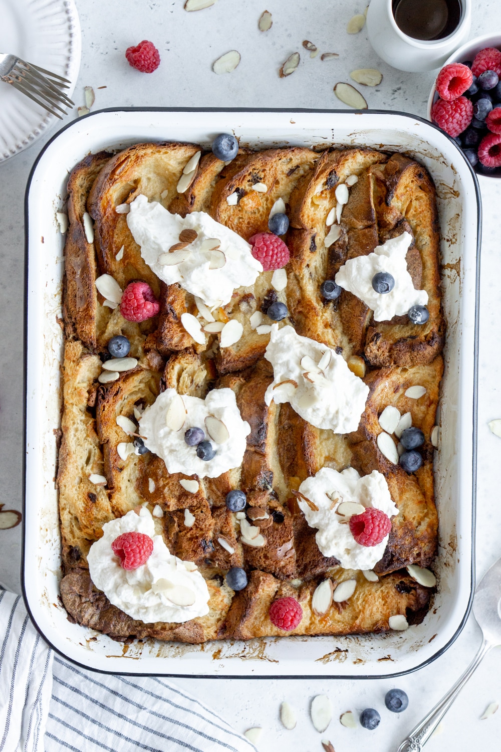 Panettone french toast in a baking dish and a bowl of fresh berries