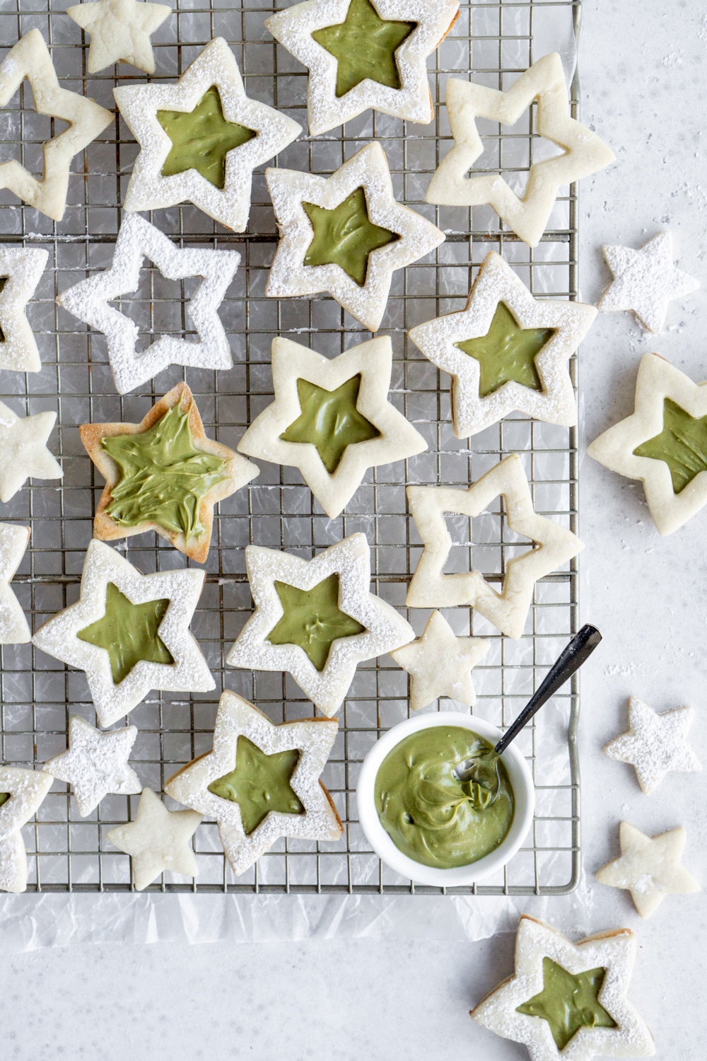 Star cookies on a cooling rack and a bowl of pistachio cream with a spoon