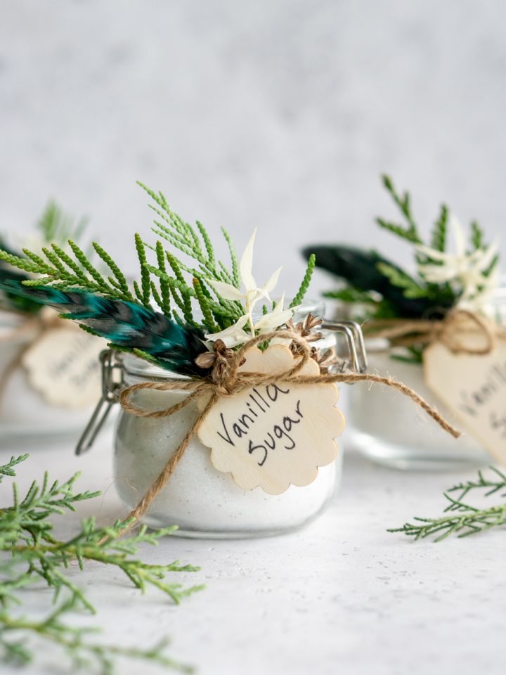Three jars of vanilla sugar decorated with fresh greenery and tags