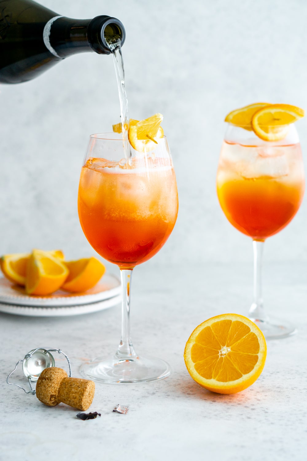 Aperol spritz - one of the easiest cocktails to make with no shaker required. You'll love it! #pinacooks #aperolspritz #summercocktail 2 glasses of aperol spritz with prosecco being poured into one glass