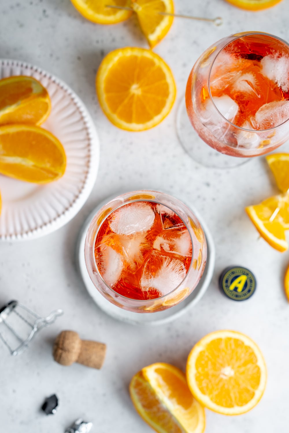 Looking for an easy cocktail? Try this 3-ingredient aperol spritz! #aperolspritz #summercocktail #pinacooks Overhead shot of 2 aperol spritz glasses with oranges scattered around