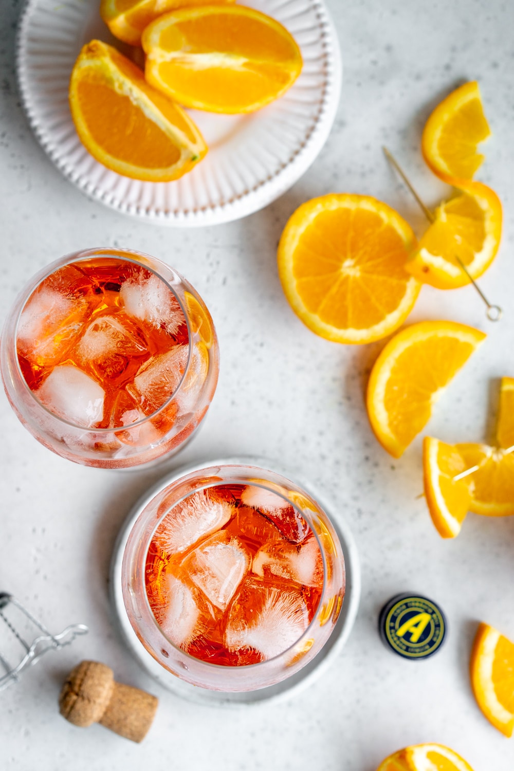 Aperol spritz - the best easy cocktail that will have you feeling like you'reoverlooking the shores of Italy on a warm summer's day! #aperolspritz #summercocktail #pinacooks 2 aperol spritz glasses with fresh oranges beside them