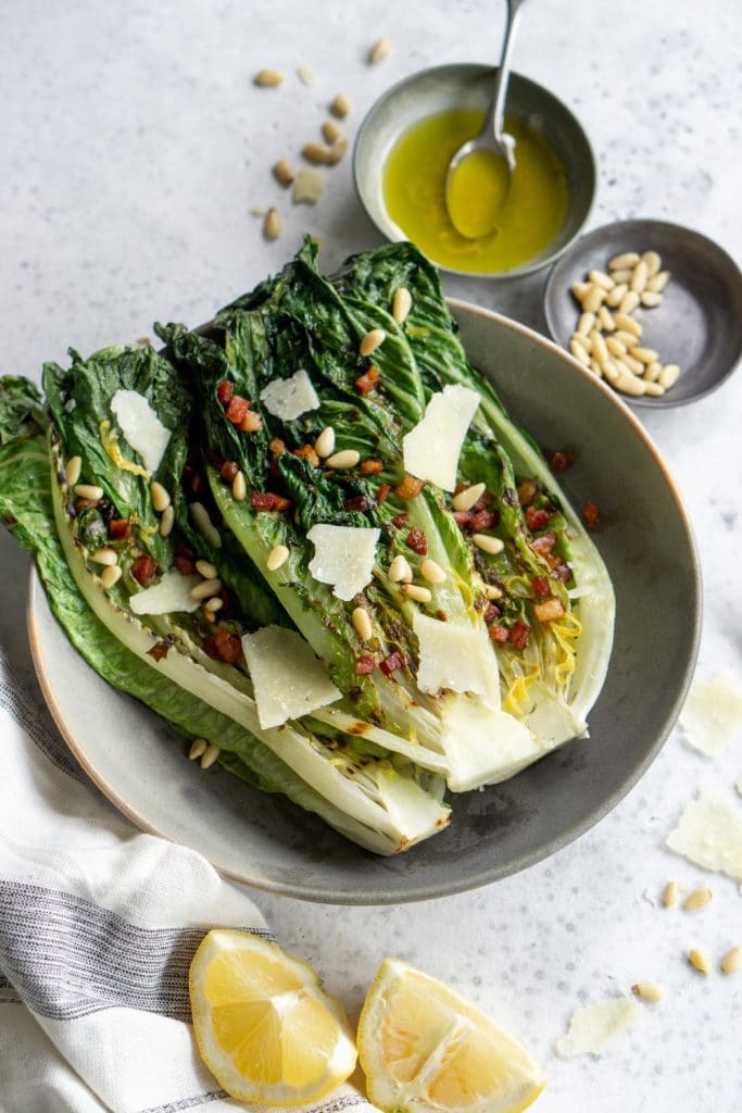 Grilled romaine salad with pine nuts and lemon vinaigrette in the background