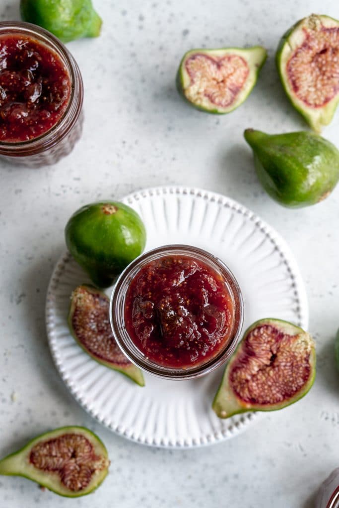 Fig jam on a white plate surrounded by cut and whole figs