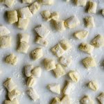 Uncooked ricotta gnocchi on a baking tray lightly dusted with flour