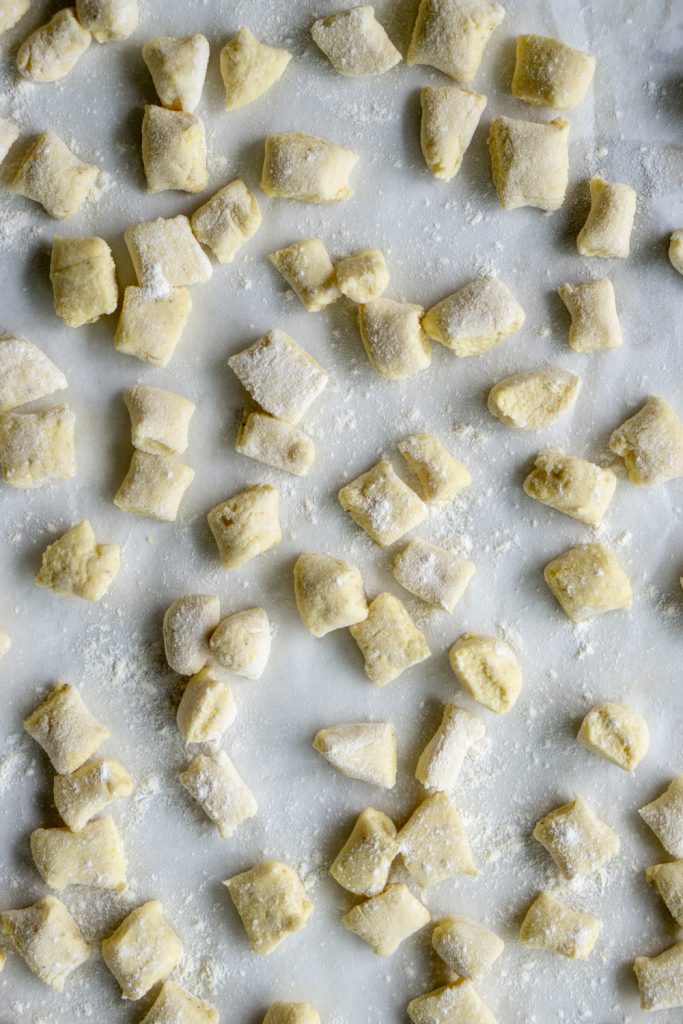 Uncooked ricotta gnocchi on a baking tray lightly dusted with flour