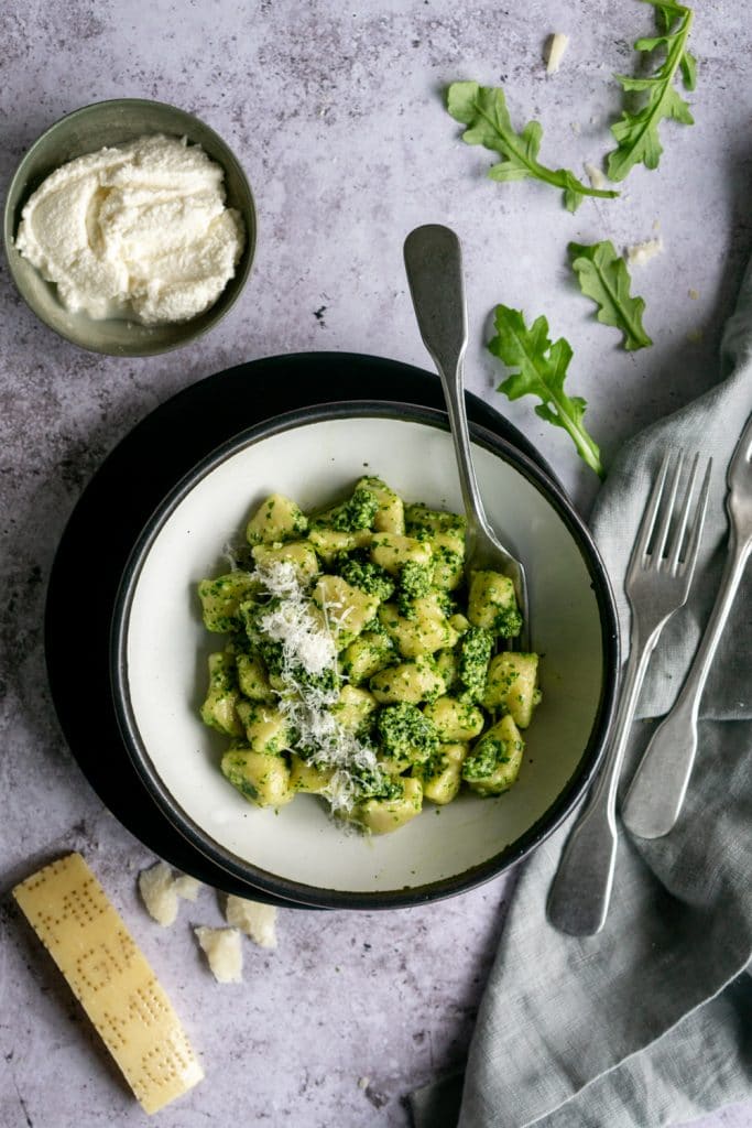Plate of cooked ricotta gnocchi dressed with arugula pesto