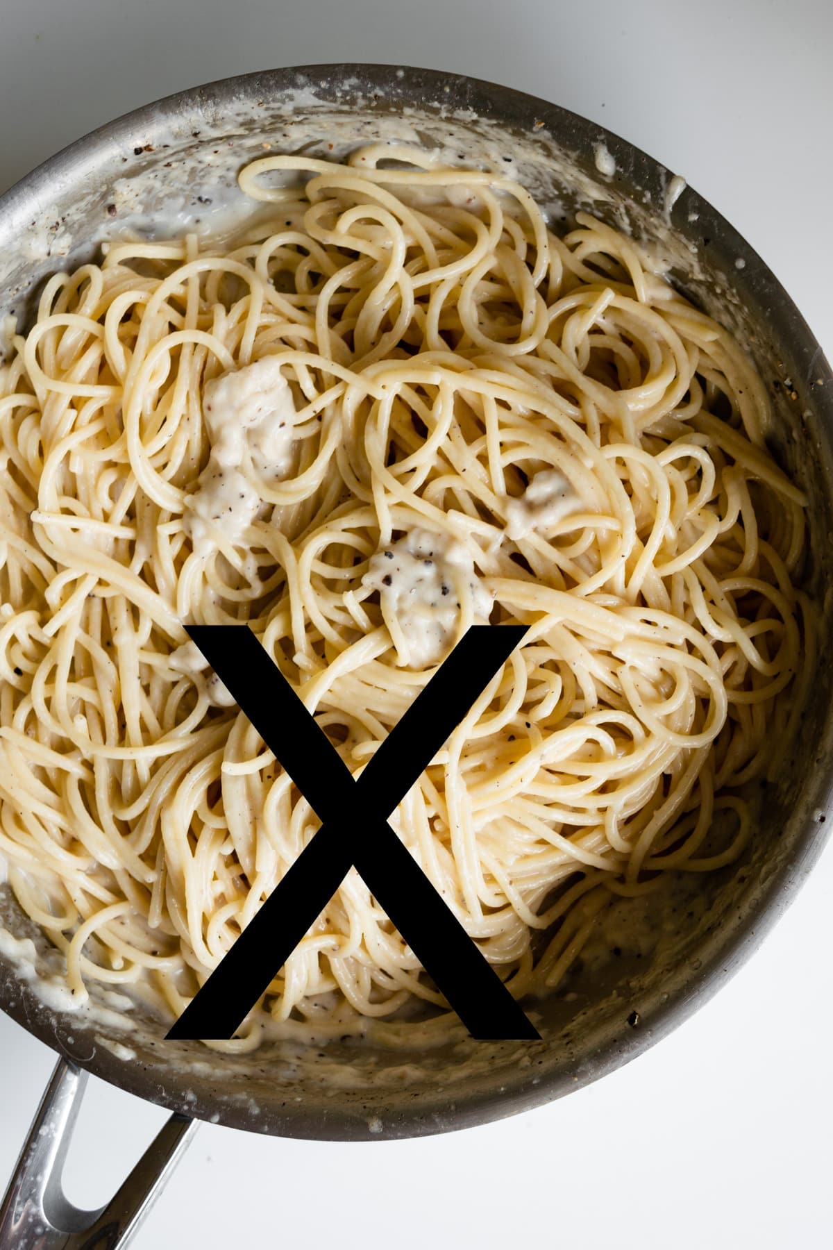Pan of cacio e pepe with cheese that has clumped/curdled