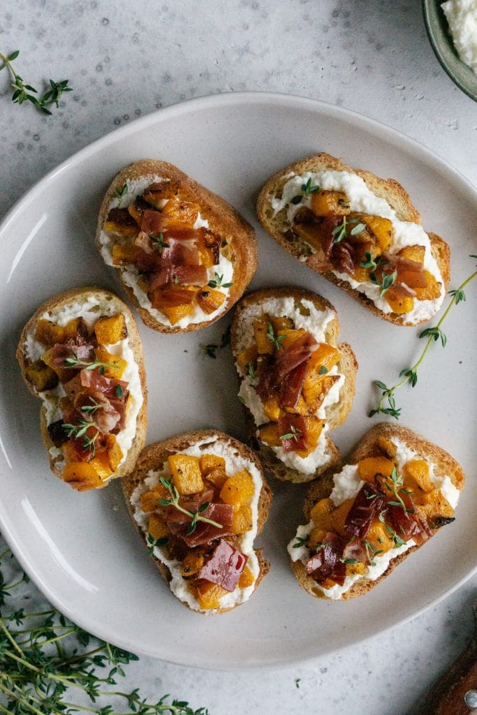 Butternut squash crostini topped with thyme in a plate