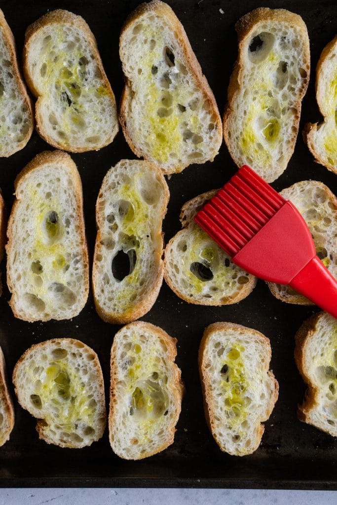 Pieces of baguette on a baking sheet brushed with olive oil
