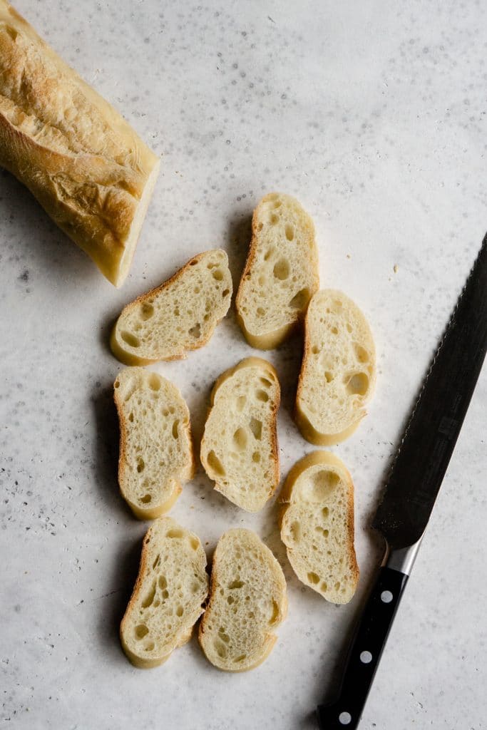 Slices of cut baguette with a knife to the side