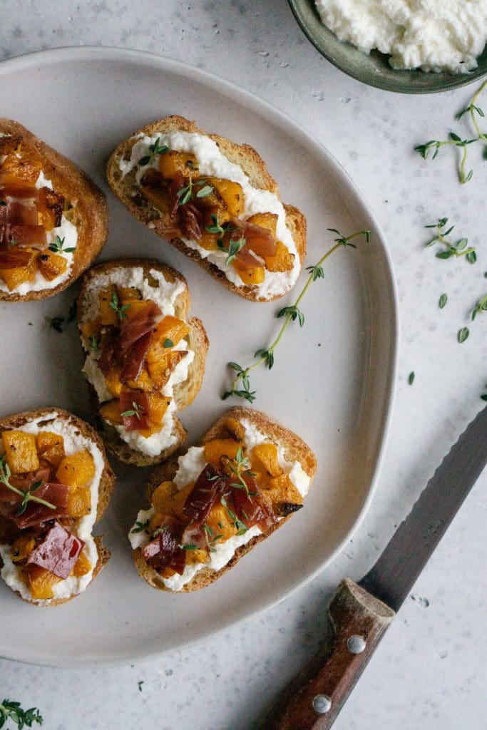 Butternut squash crostini in a plate with a knife to the side